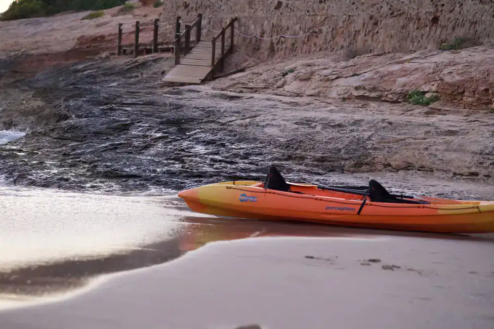 Solo touring kayak parked on a rocky shoreline