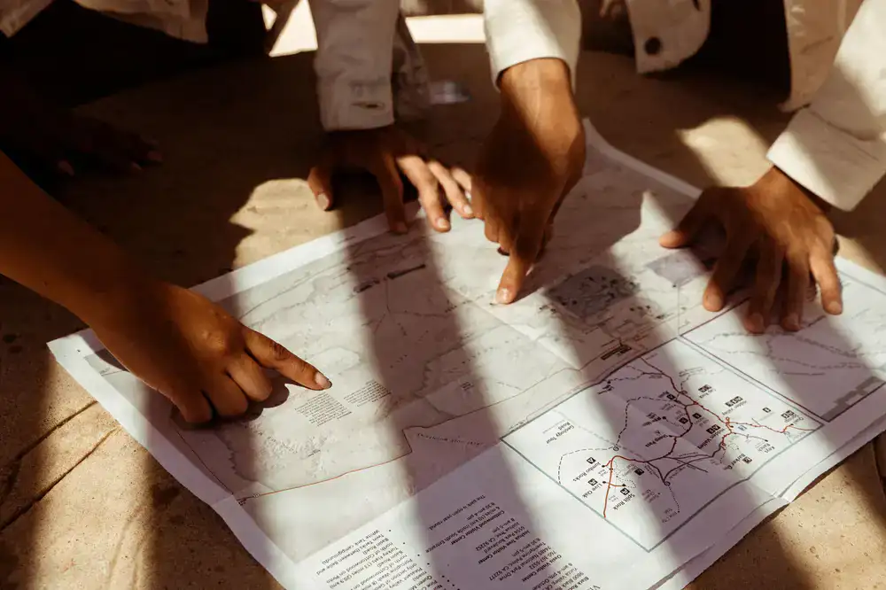 A person pointing at an open map near the water