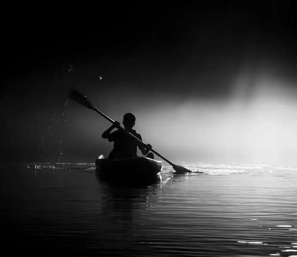 Kayaker paddling through a narrow natural channel